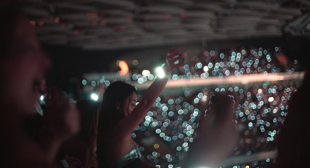 Crowd of fans cheering at a live concert with lights
