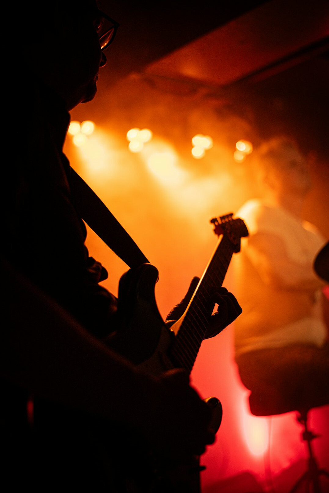 Musician playing guitar under concert stage lights